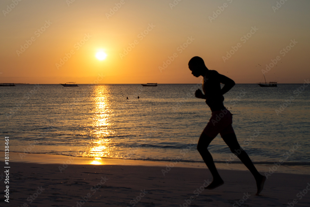 силуэты людей, занимающихся спортом на пляже во время захода солнца
