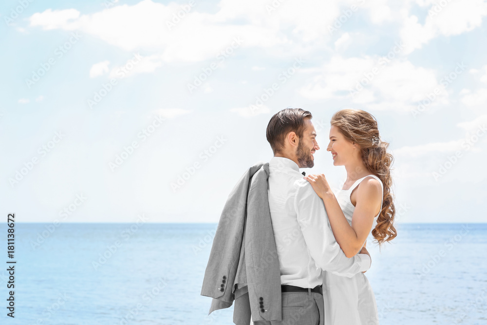 Happy newlywed couple hugging on seashore Happy newlywed couple hugging on seashore