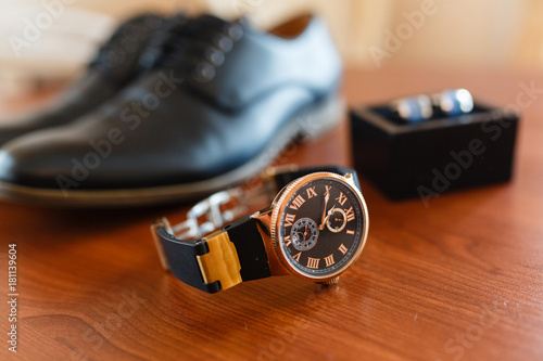 Set of the groom, expensive clock on the background of cufflinks in a box, classic leather shoes, mens accessories of a businessman on a wooden table. top view with place for text