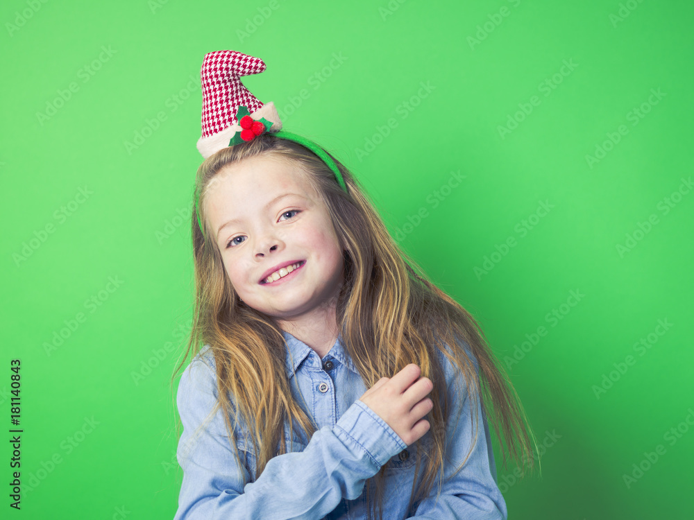 young girl with christmas decoration on head in front of green background young girl with christmas decoration on head in front of green background