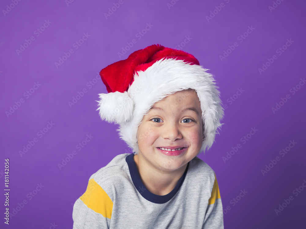 young 5 year old boy with christmas decoration on his head in front of violet background