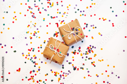Gift boxes wrapped in kraft paper with confetti on white background. Top view