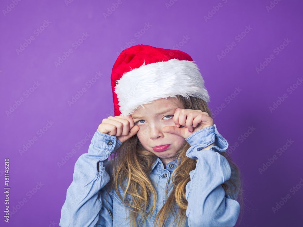 girl with christmas hat on her head in front of violet background girl with christmas hat on her head in front of violet background