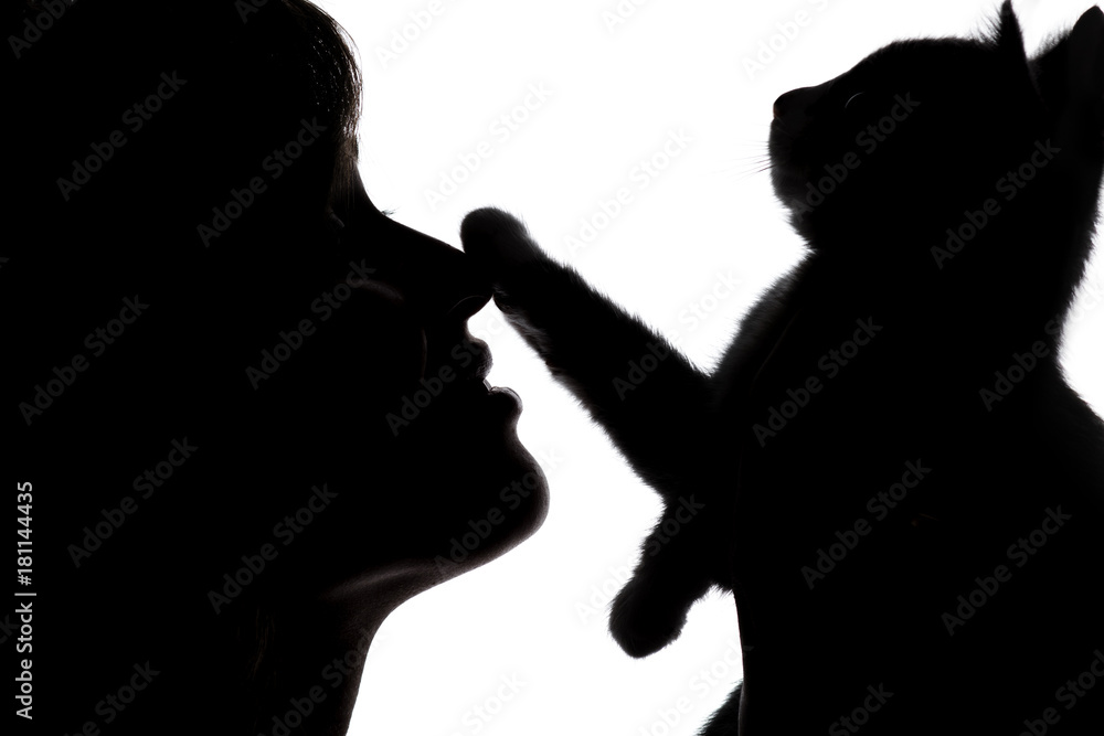 silhouette of a female face with a small kitten that put a paw on the nose of girl on white isolated background