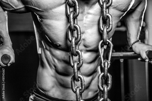 Brutal bodybuilder working out in gym with chain.