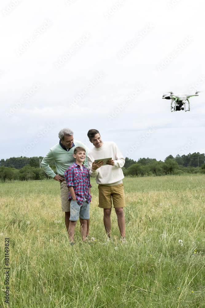 Multigenerational family flying drone in field Multigenerational family flying drone in field