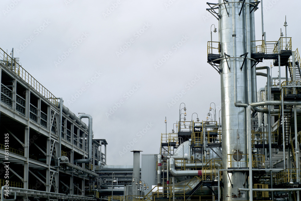 Section of the distillery plant of a modern oil refinery with a fractionating column, tanks and pipelines Section of the distillery plant of a modern oil refinery with a fractionating column, tanks and pipelines