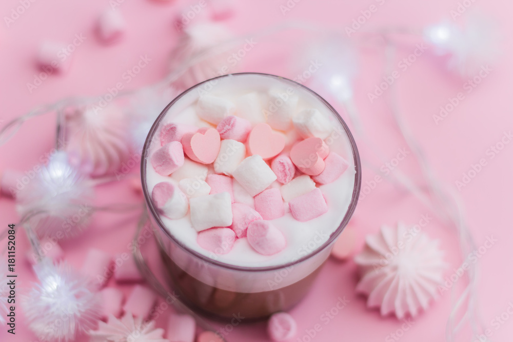 Top view hot beverage with whipped cream,marshmallows and heart shaped chocolate candies on pink pastel background Top view hot beverage with whipped cream,marshmallows and heart shaped chocolate candies on pink pastel background