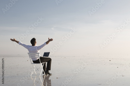 Business man with laptop working on the beach