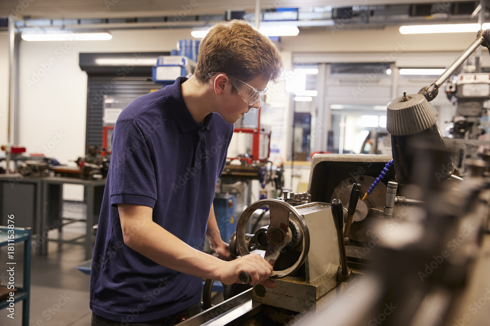 Male Teenage Apprentice In Engineering Factory Using Lathe Male Teenage Apprentice In Engineering Factory Using Lathe