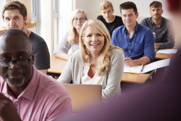 Male Tutor Teaching Class Of Mature Students Viewed From Behind
