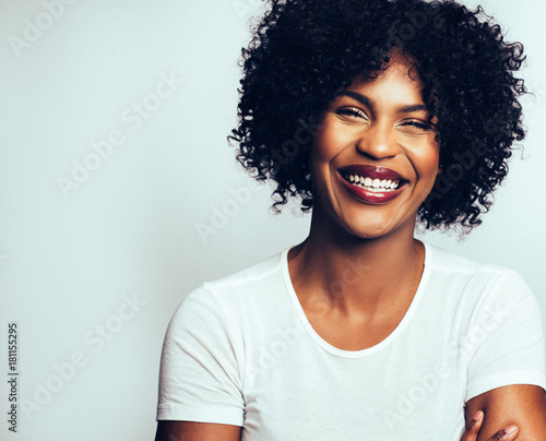 Laughing young African woman standing confidently with her arms © Flamingo Images