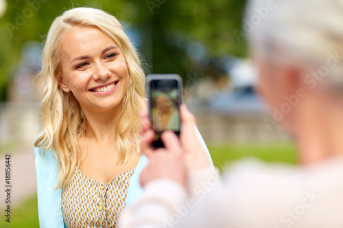 senior mother photographing daughter by smartphone