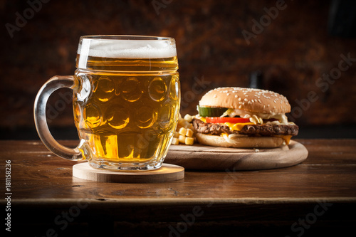 A glass of fresh cold light beer with gourmet hamburgers and wheat in a bar and a dark pub