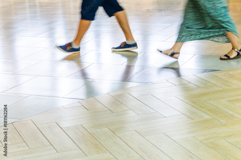 Obraz premium People walking on the tiled floor - Detail of legs and shoes moving on sidewalk in mall. Blur in Motion, Long Exposure. Abstract Background