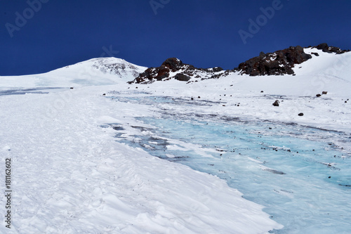 glacier among the rocky mountains. blue sky in the background. snow-capped peaks of the ridge