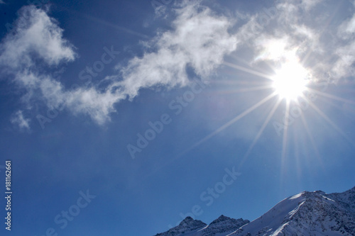 the sun shines through the clouds. the snow lies on the mountain peaks.