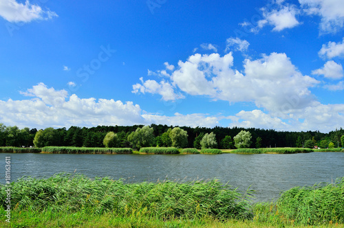 Białe chmury na tle nieba nad jeziorem w słoneczny dzień.