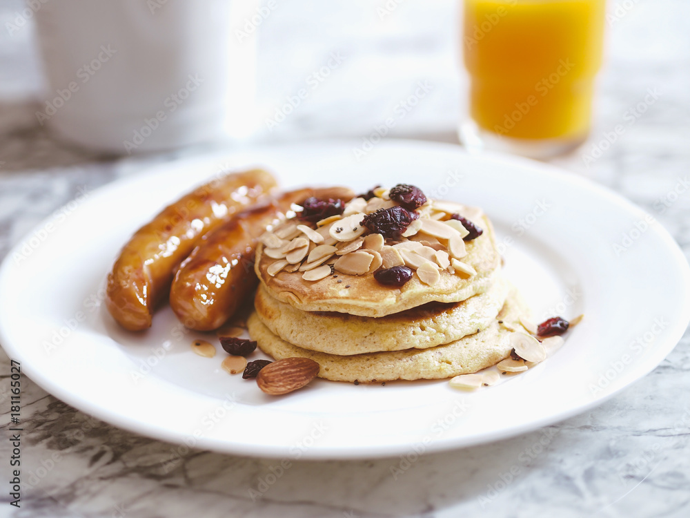 Breakfast Pancake and Sausage Top with Almond and Raisin on white plate Breakfast Pancake and Sausage Top with Almond and Raisin on white plate
