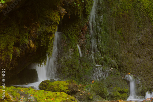 Smoll waterfall among rocks covered with green moss