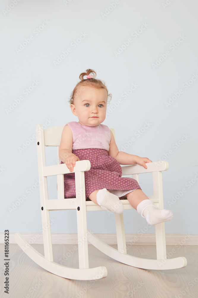 beautiful little girl in a dress sits on a white chair beautiful little girl in a dress sits on a white chair