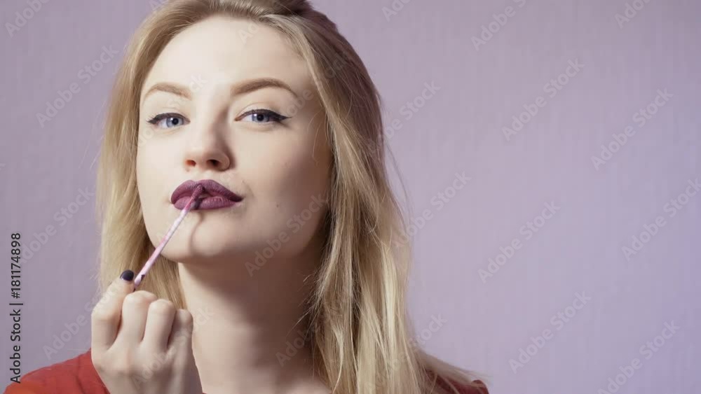 Beautiful girl paint her lips with purple lip gloss Beautiful girl paint her lips with purple lip gloss