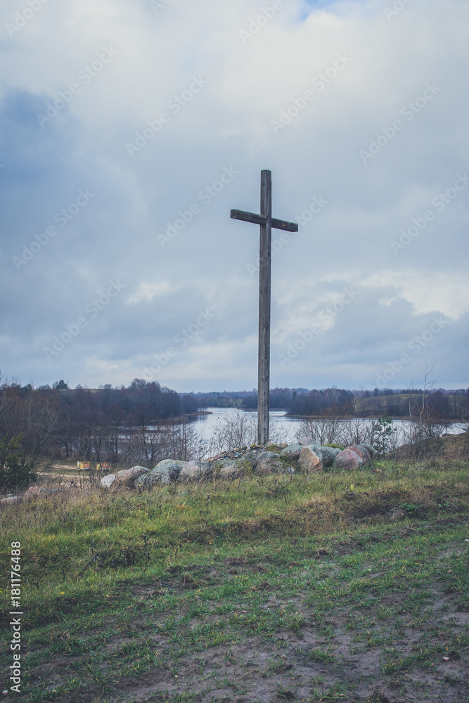 Peasant wooden cross on the mountain near the river bank, lake.