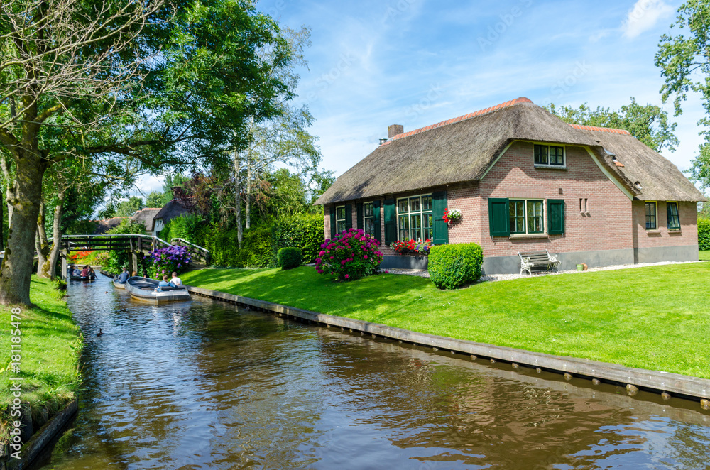Giethoorn, Netherlands: View of famous Giethoorn village with canals and rustic thatched roof houses.The beautiful houses and gardening city is know as Giethoorn, Netherlands: View of famous Giethoorn village with canals and rustic thatched roof houses.The beautiful houses and gardening city is know as