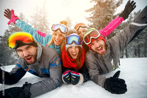 Group of friends on winter holidays - Skiers lying on snow and having fun