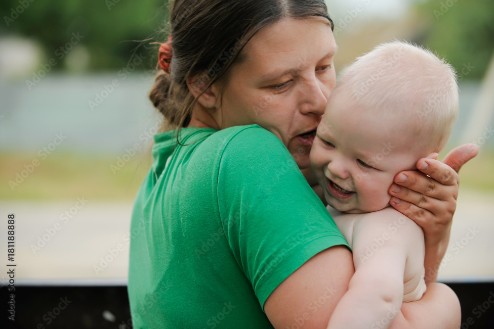 A happy mother holds a young son in her arms. Focusing in the foreground. Background is blurred. A happy mother holds a young son in her arms. Focusing in the foreground. Background is blurred.