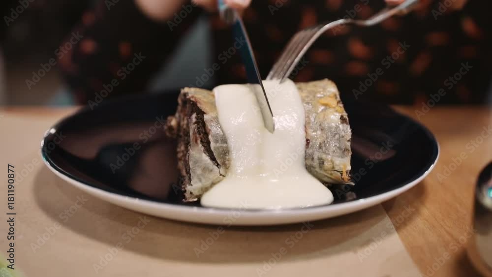 Unrecognizable girl eating dessert black strudel at the restaurant using fork and knife. Slow motion Close-up.