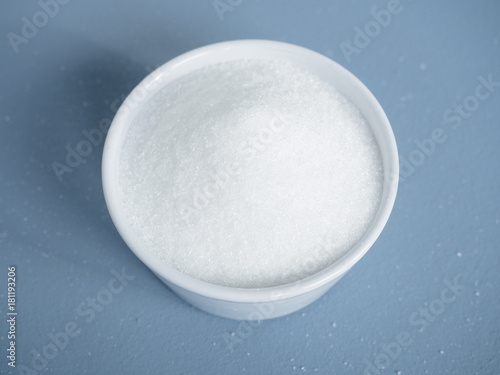 Schilderij op canvas Close up of portion of white sugar in small white bowl on blue background used a