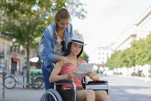 two friends visiting foreign city one sitting in wheelchair
