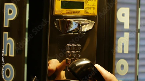 Woman picks up and dials from public telephone payphone - close up photo