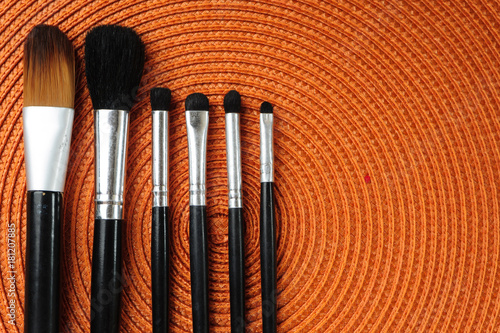 a selection of orange brushes with different sizes on a white surface with some paper sheets, art tools background photo