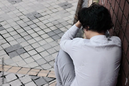 Back view of frustrated stressed young Asian employee man touching head and feeling disappointed or exhausted. Unemployed businessman concept.