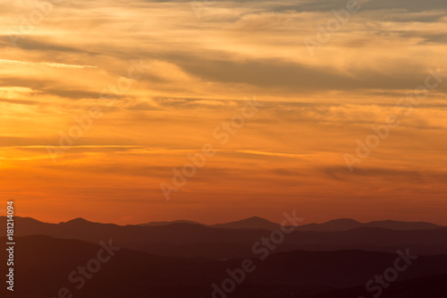 A silhouette of a mountain peak at sunset, under a big sky with beautiful red and yellow clouds © Massimo