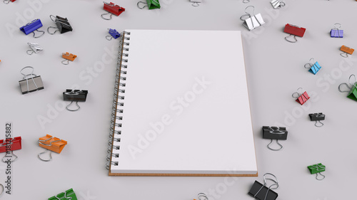 Blank spiral notebook with colorful binder clips on white table