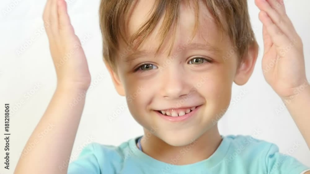 A close-up of a child with joy and a smile looks at the camera, holding his hands behind his head, covering his ears. The boy shows joy and a smile, positive emotions. A close-up of a child with joy and a smile looks at the camera, holding his hands behind his head, covering his ears. The boy shows joy and a smile, positive emotions.