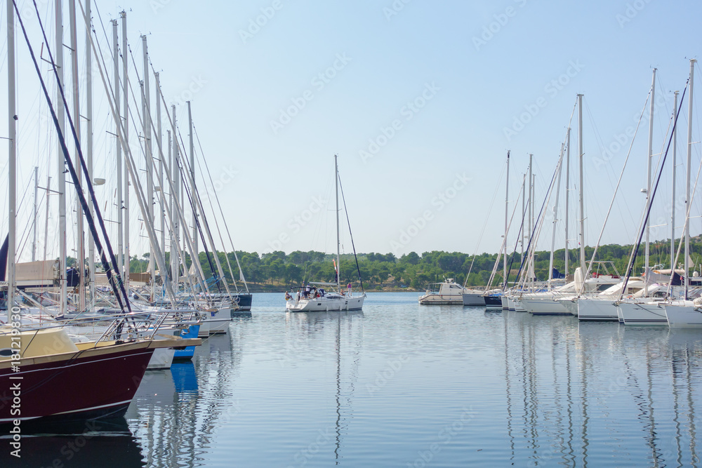 Fototapeta premium Sailboat leaving harbor, Yachts and boats parked in harbor, sunrise, morning