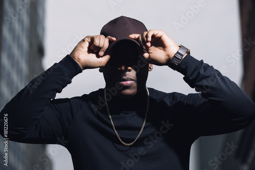 Brutal man rapper with cap posing in city