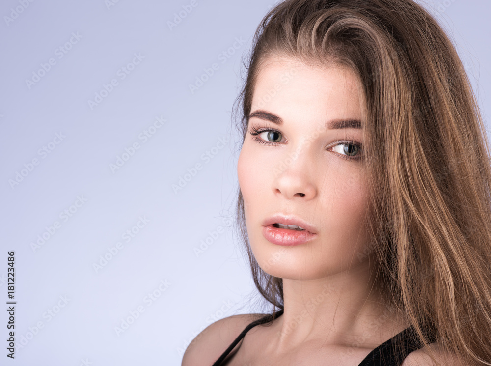 Naklejka premium Horizontal closeup portrait of a young beautiful woman with long flowing hair. Light make-up