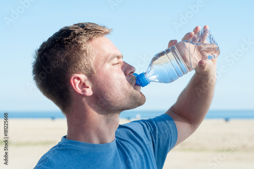 Portrait of man drinking water on beach