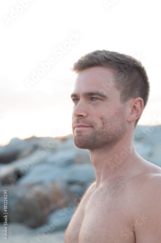 Portrait of topless man by the rocks at the beach