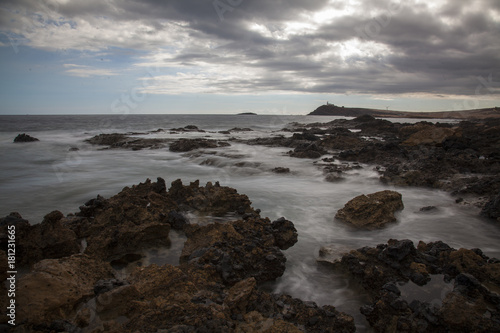 Rough coast with water running through the rocks. Dark clouds in the sky.