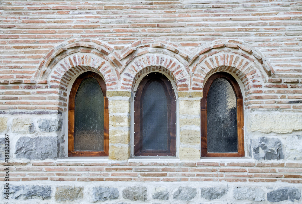Three small arch windows on a brick wall