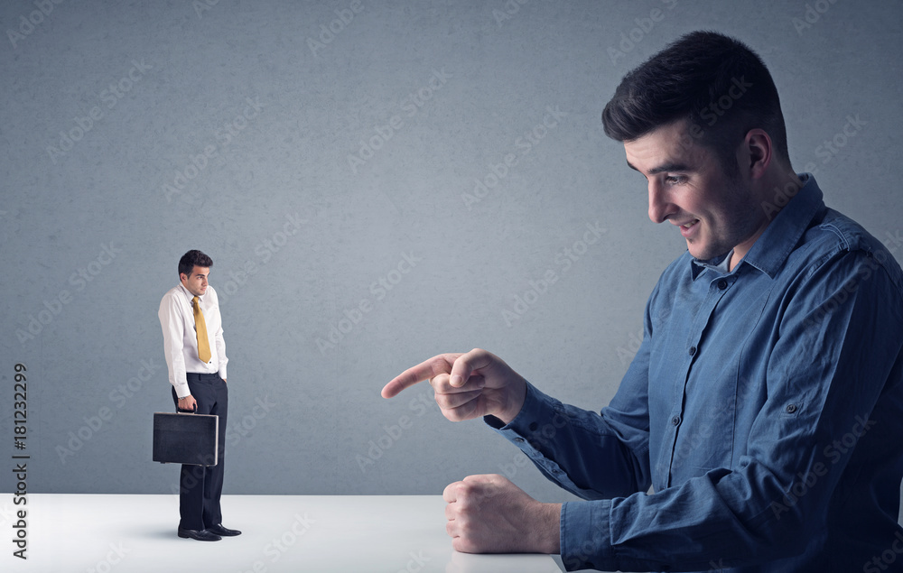 Young businessman fighting with miniature businessman Young businessman fighting with miniature businessman