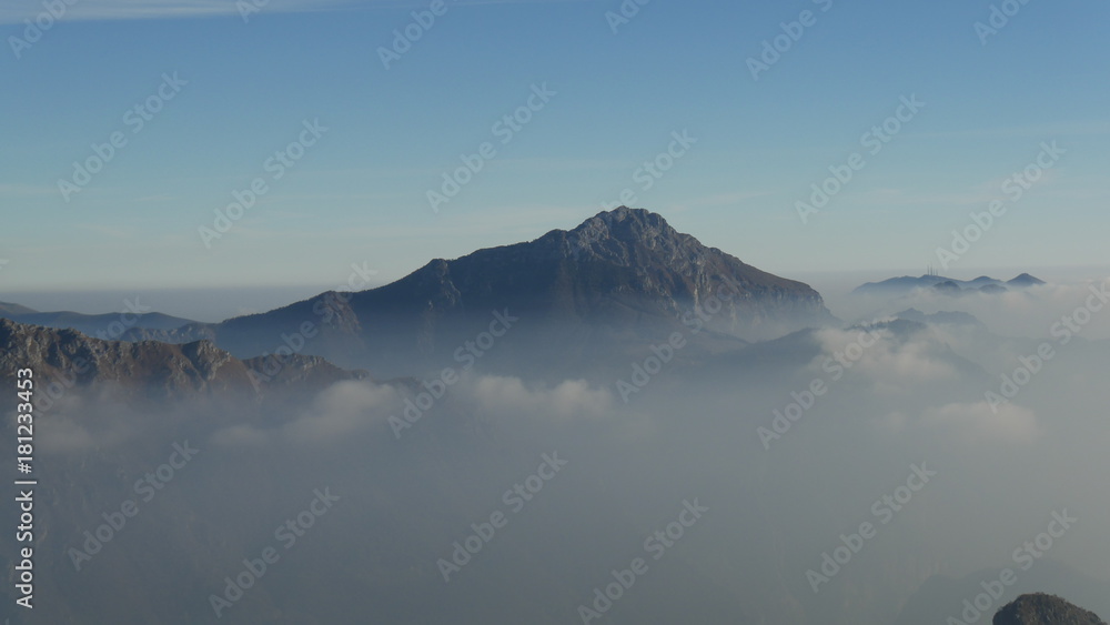 Panorama dalla vetta della montagna sulle Alpi con nebbia e nuvole in pianura
