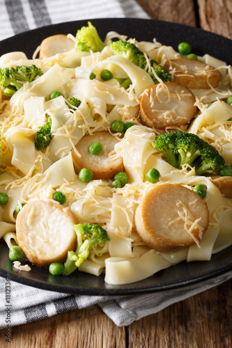 Delicious pasta with fried mushrooms, cheese, broccoli and peas close-up. vertical