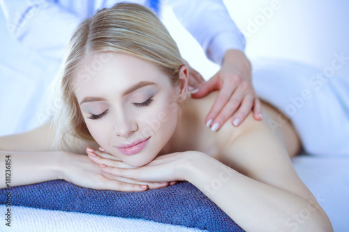 Young woman lying on a massage table,relaxing with eyes closed. Woman. Spa salon